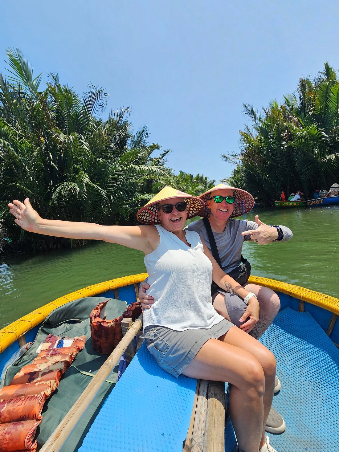 Happy tourists wearing traditional conical hats on a bamboo basket boat ride in Cam Thanh Coconut Forest during their Hoi An Private Day Tour.