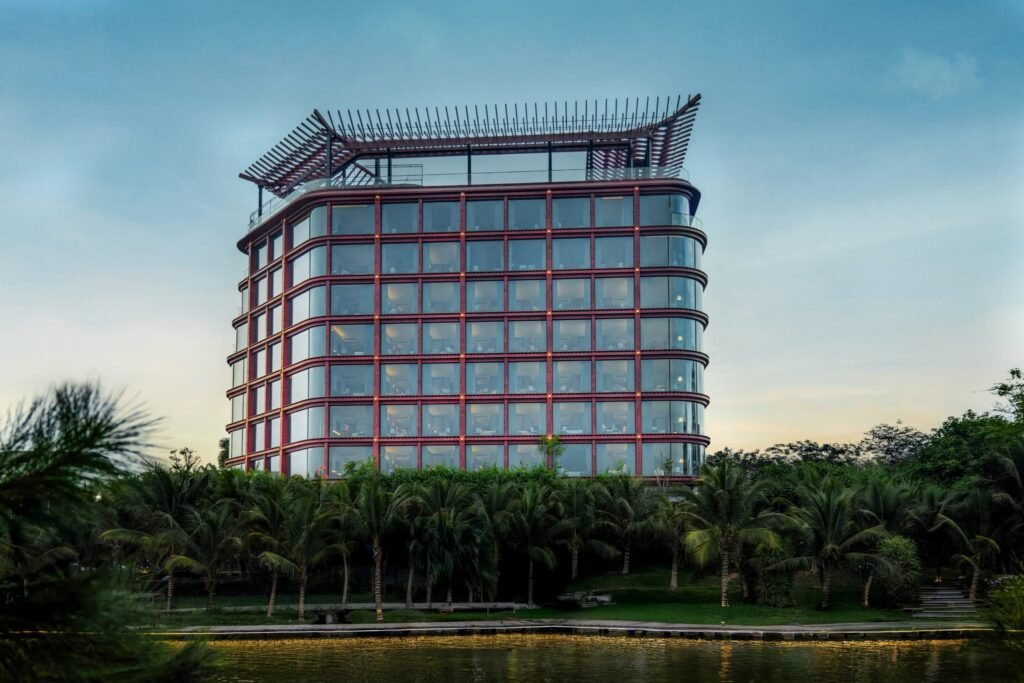 Exterior view of Dusit Le Palais Tu Hoa Hanoi hotel showing the unique reddish-brown lattice facade and West Lake frontage.